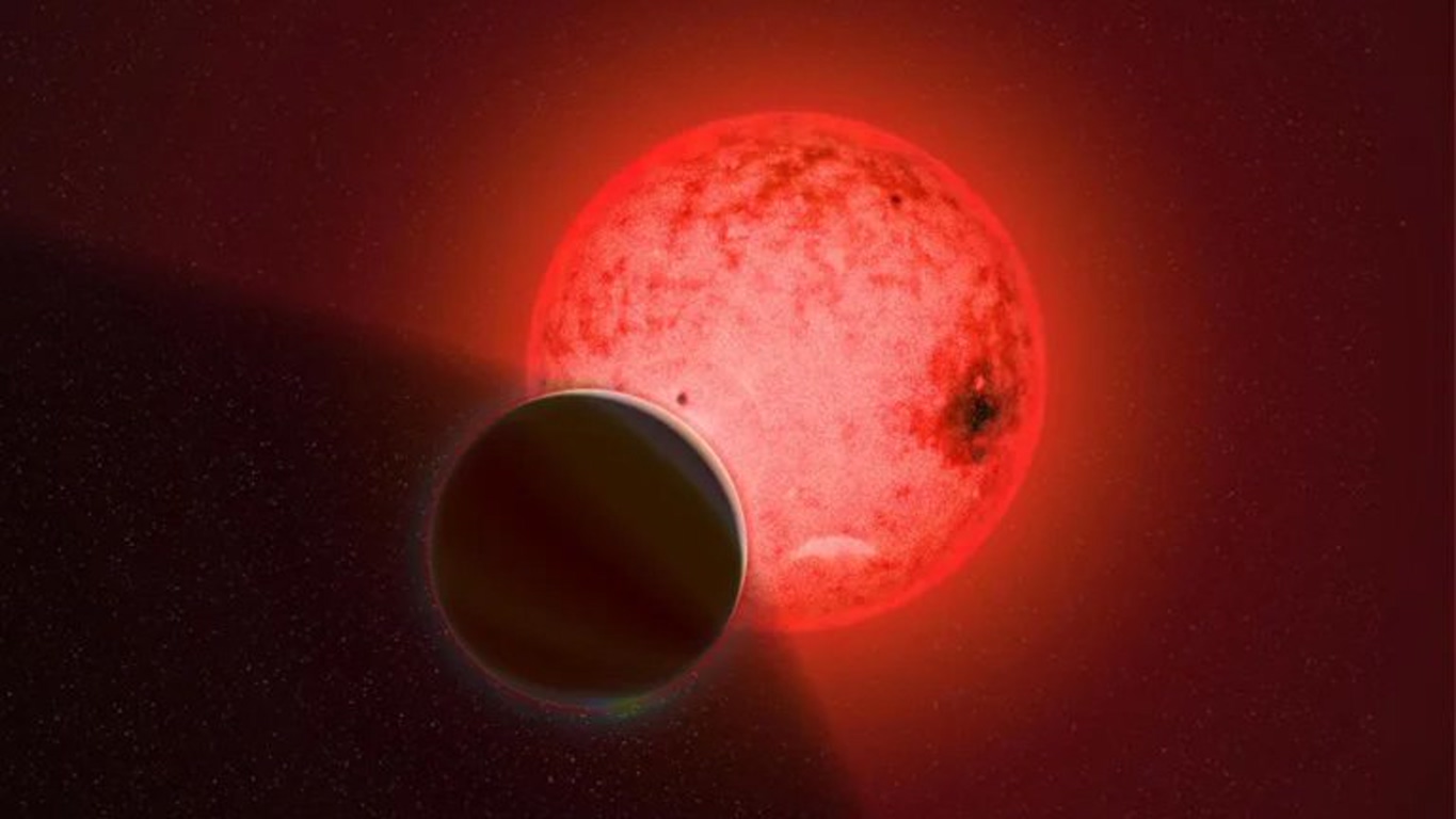 Dark planet silhouetted as it passes in front of a glowing red star in space (planetary transit)