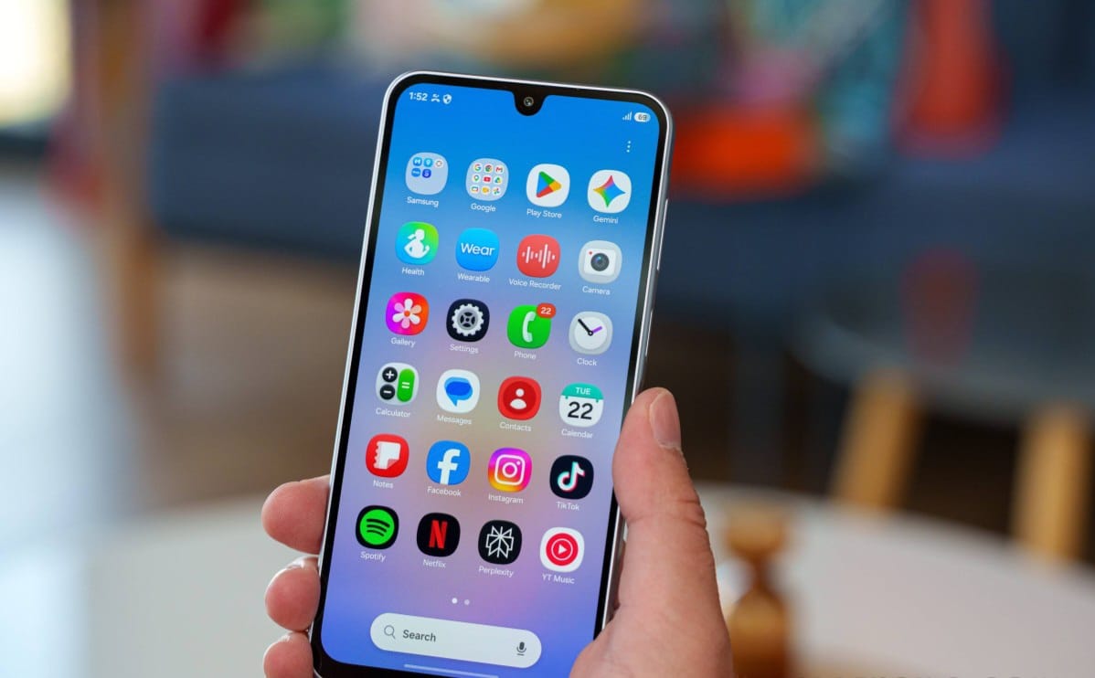 Hand holding a smartphone displaying a home screen full of app icons in a colorful grid.