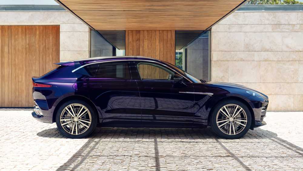Dark blue SUV parked on a cobblestone driveway in front of a modern house with wooden doors and stone walls.