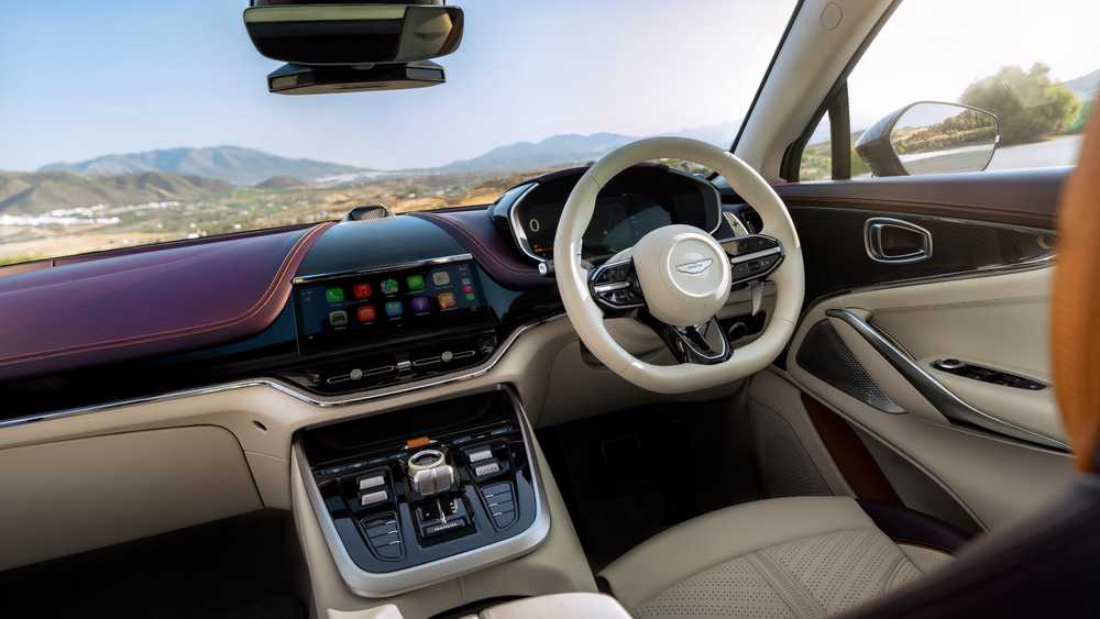 Luxurious car interior with beige leather seats, digital dashboard, and center console control panel; view of mountains outside through windshield