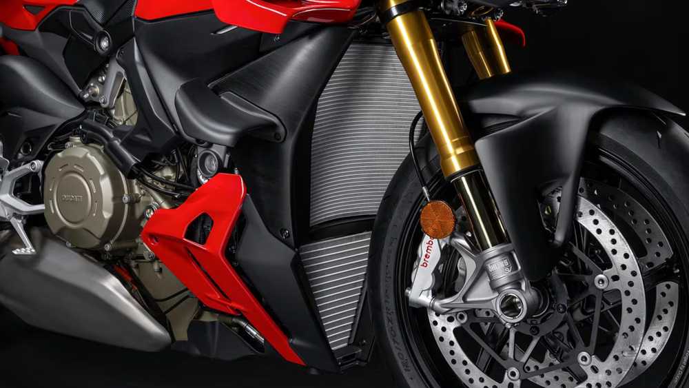 Close-up of a red sport motorcycle's front section with gold suspension forks, Brembo brake caliper, and large ventilated brake disc