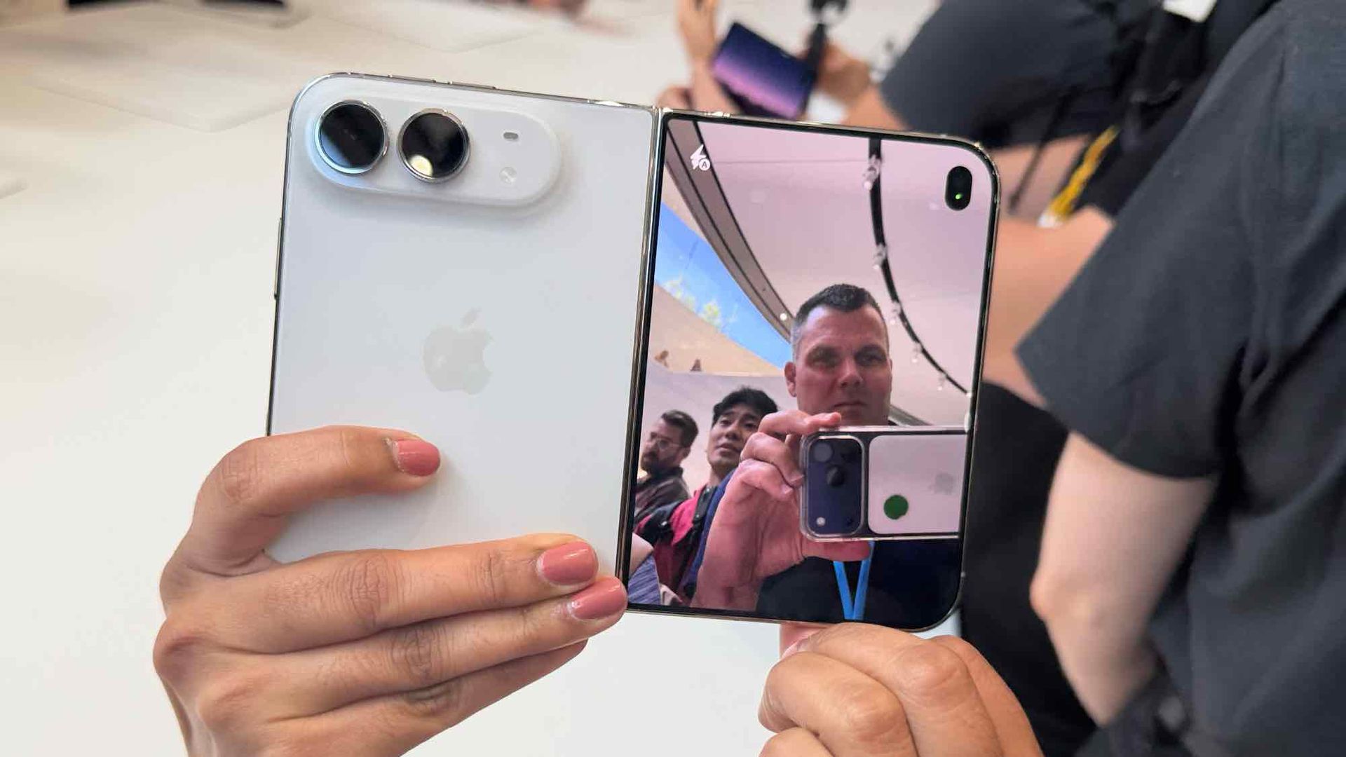 Two smartphones held together, one showing a reflection of people taking a photo in a showroom setting.