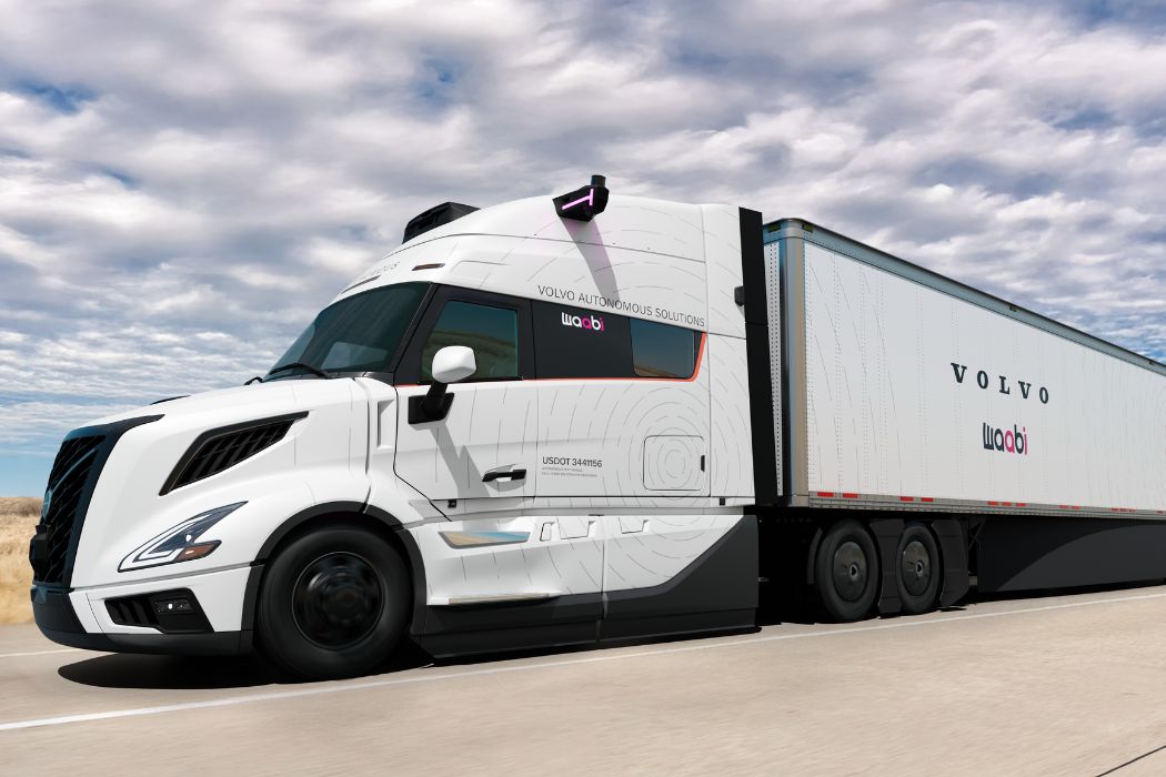 White Volvo autonomous truck with a long trailer driving on a highway under a cloudy sky.