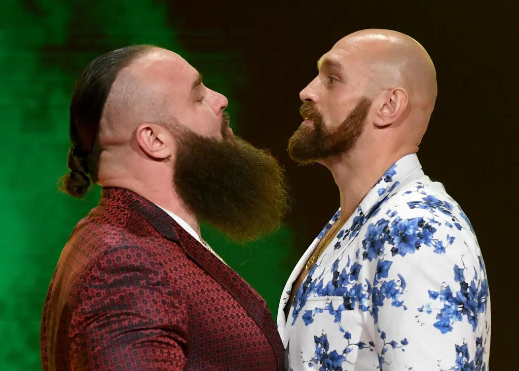 Two bearded men in bold jackets face off, noses inches apart, on a stage with green lighting.