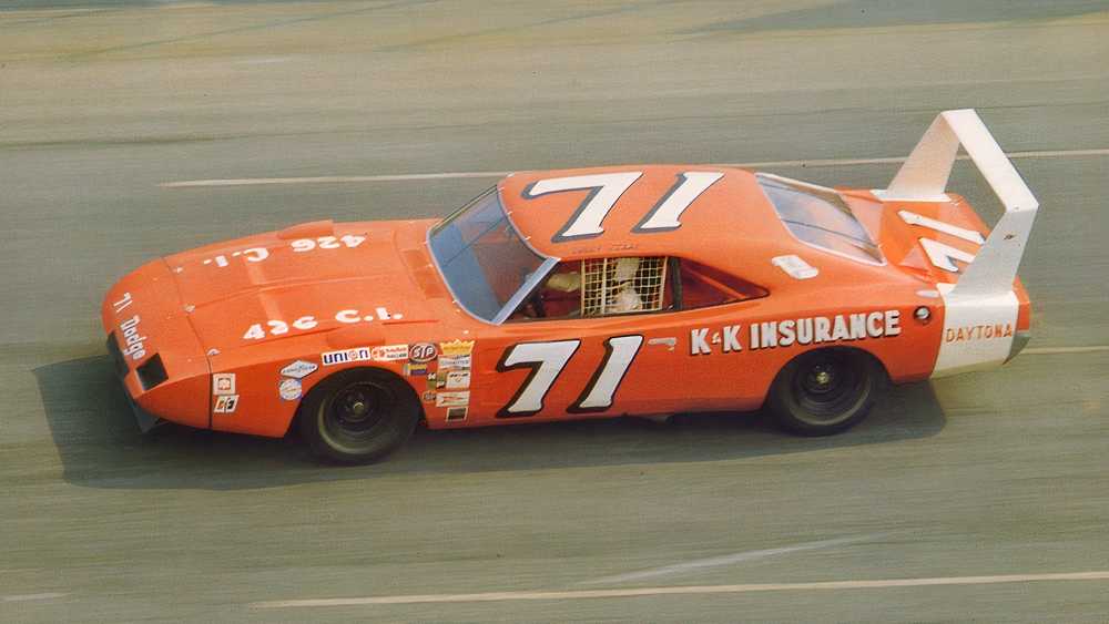 Orange race car #71 on a track, sponsors decals along the side and a large rear wing labeled Daytona/71.