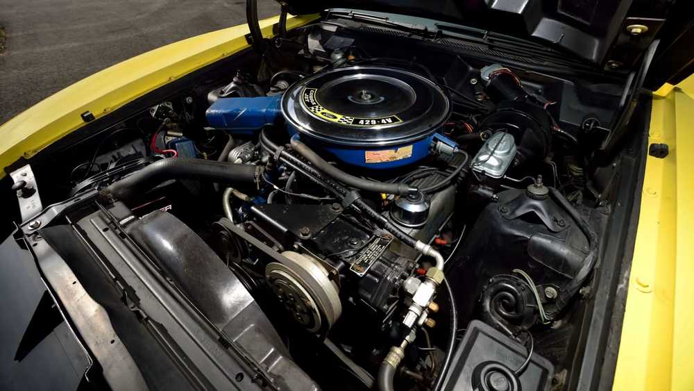 Close-up of a car engine bay with a blue air cleaner, belts, and yellow body panels visible around the edges.” ,“V8 engine under the hood of a yellow car, showing the blue air cleaner and several hoses and pulleys.” ,“Engine compartment of a yellow sports car with exposed belts, hoses, and a round air filter atop the engine.” ,“High-performance car engine with a blue circular air filter housing, mounted in a yellow-painted engine bay.” ,“Detailed view of a car’s engine bay: yellow exterior, black components, and silver pulley system.”]} }Oops, there is a stray quote and formatting. Let's fix. Provide proper JSON with array of strings. Let's produce final. Sorry. Let's craft correctly. Ensure no stray punctuation. Let's output. ] In final.']]} Wait must be valid. I'll provide: {