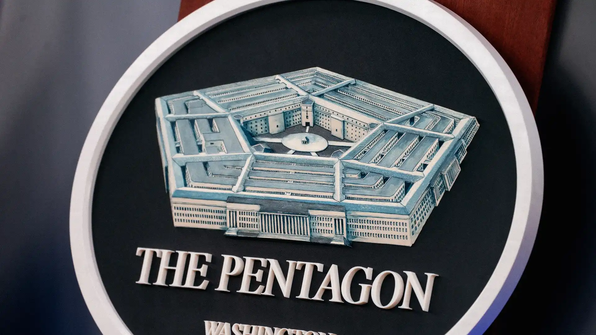 Circular sign featuring a blue model of the Pentagon inside a round emblem with the words THE PENTAGON, Washington D.C.