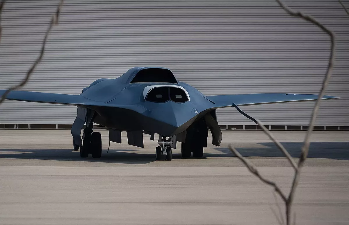 Front view of a gray B-2 Spirit stealth bomber on a tarmac with landing gear down.