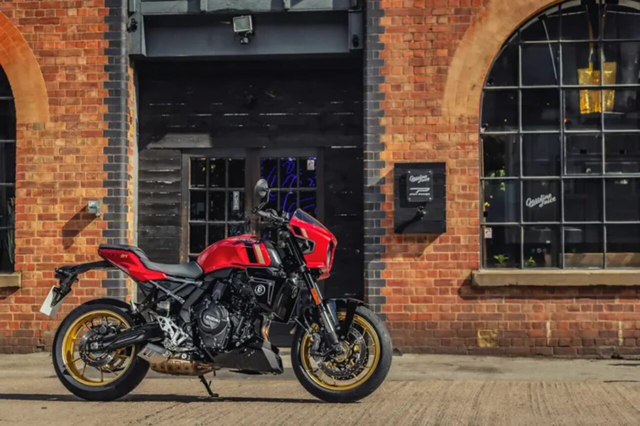 Red sport motorcycle parked on a brick street in front of a garage-style building with large arched windows and black doors.