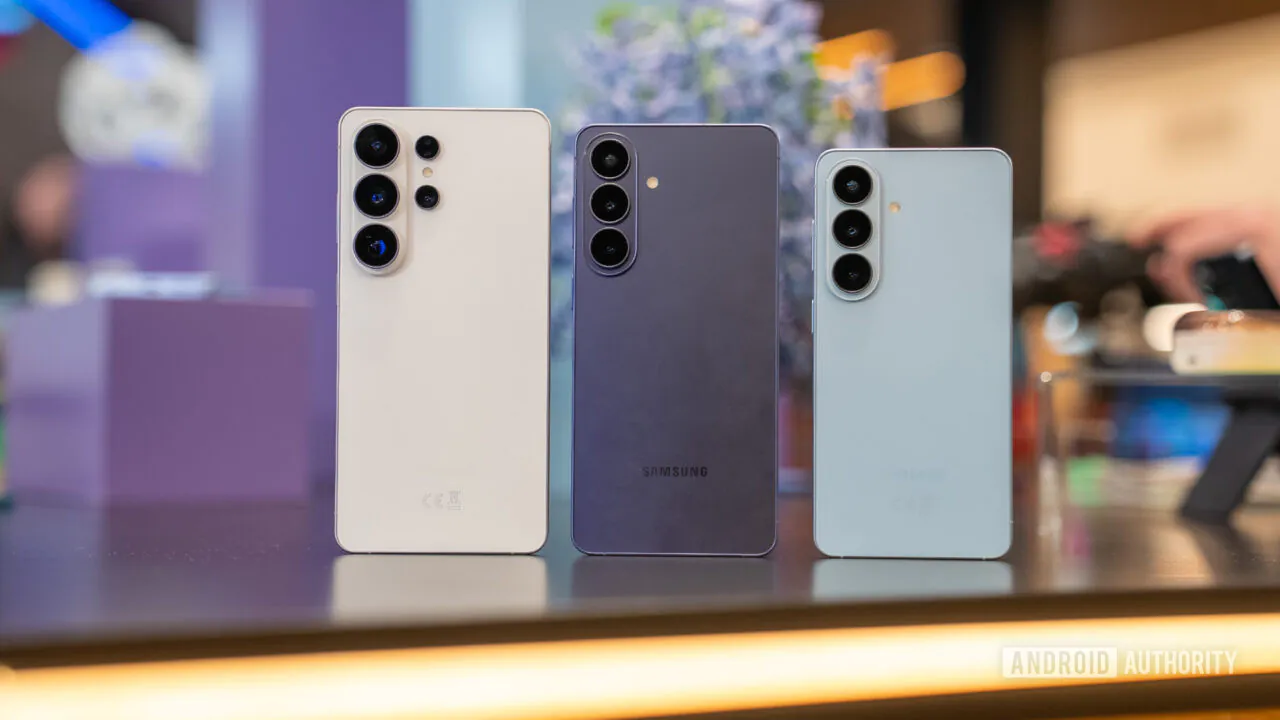 Three Samsung Galaxy smartphones stand upright on a display table, showing their rear camera arrays (white, purple, and light blue).