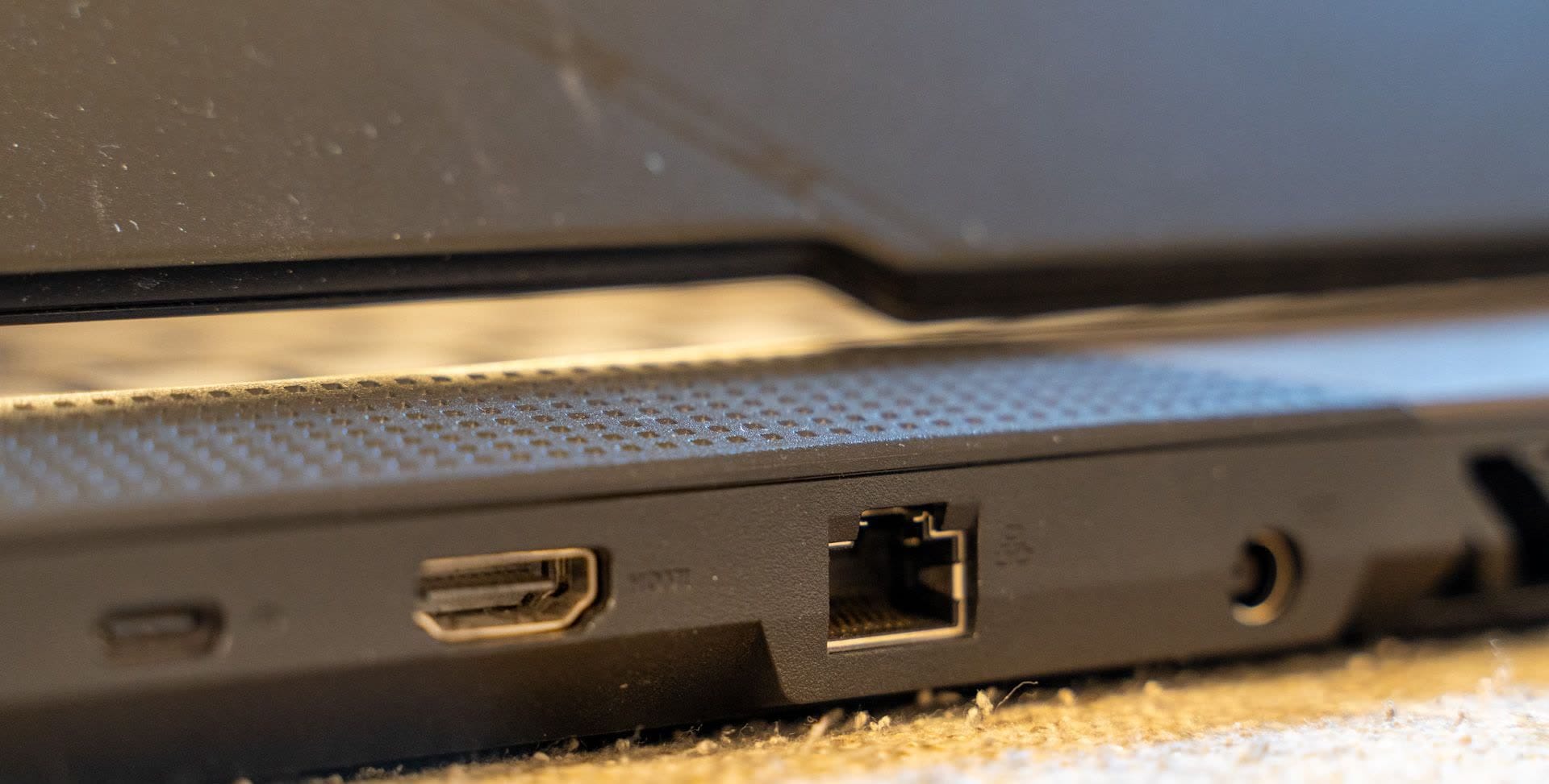 Close-up of a laptop's back edge showing an HDMI-like port, an Ethernet jack, and other connectors on a perforated vent panel
