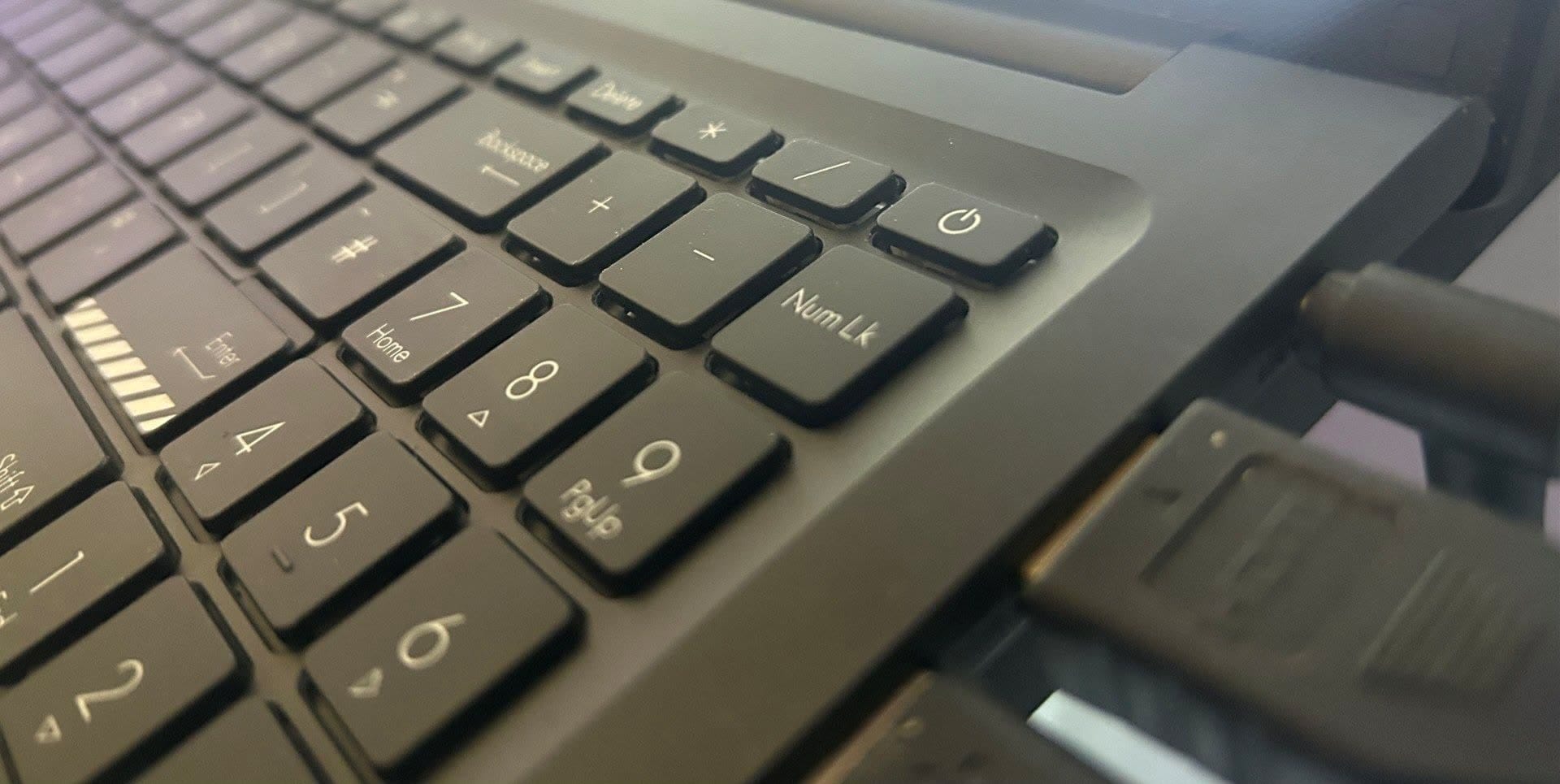 Close-up of a dark laptop keyboard showing the number pad and power button in the upper-right corner.