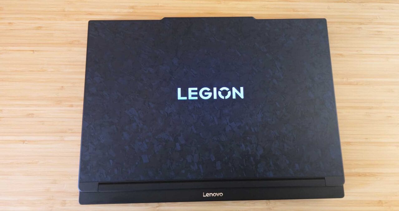 Top-down view of a closed Lenovo Legion laptop on a light wooden surface, centered logo visible.