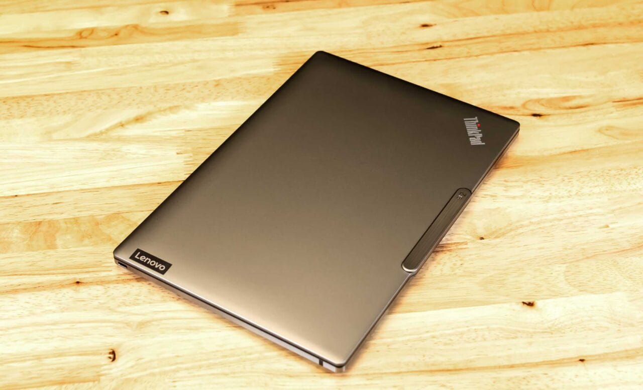 Closed Lenovo ThinkPad laptop on a light wooden table surface, viewed from top-left corner.