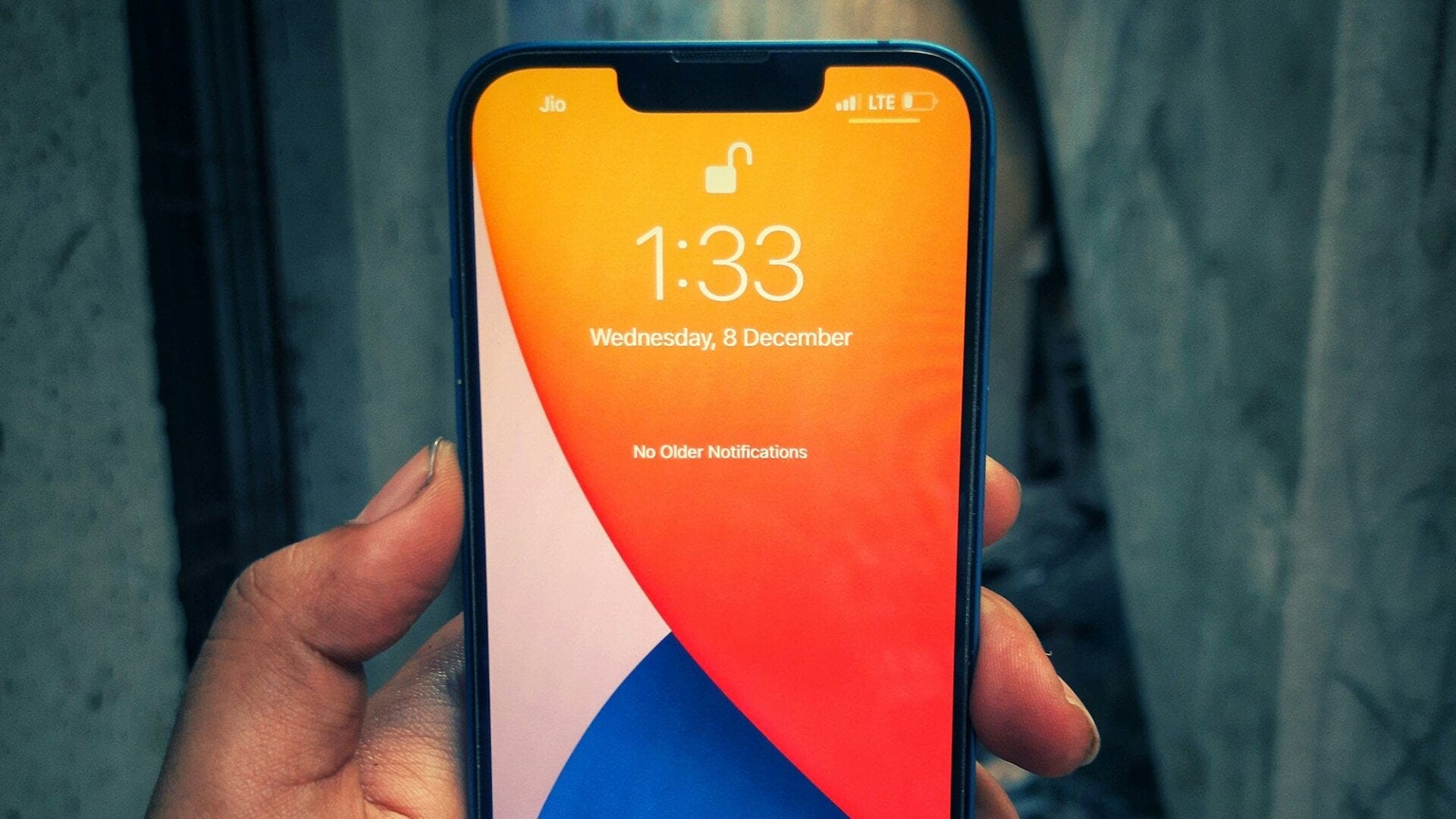 Hand holding a smartphone displaying time 1:33 and the date Wednesday, 8 December, on an orange gradient lock screen with 'No Older Notifications' text.