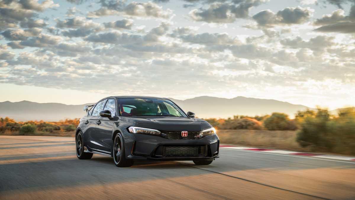 Gray Honda sedan drives along a winding desert highway at sunset, mountains in the distance and golden light.