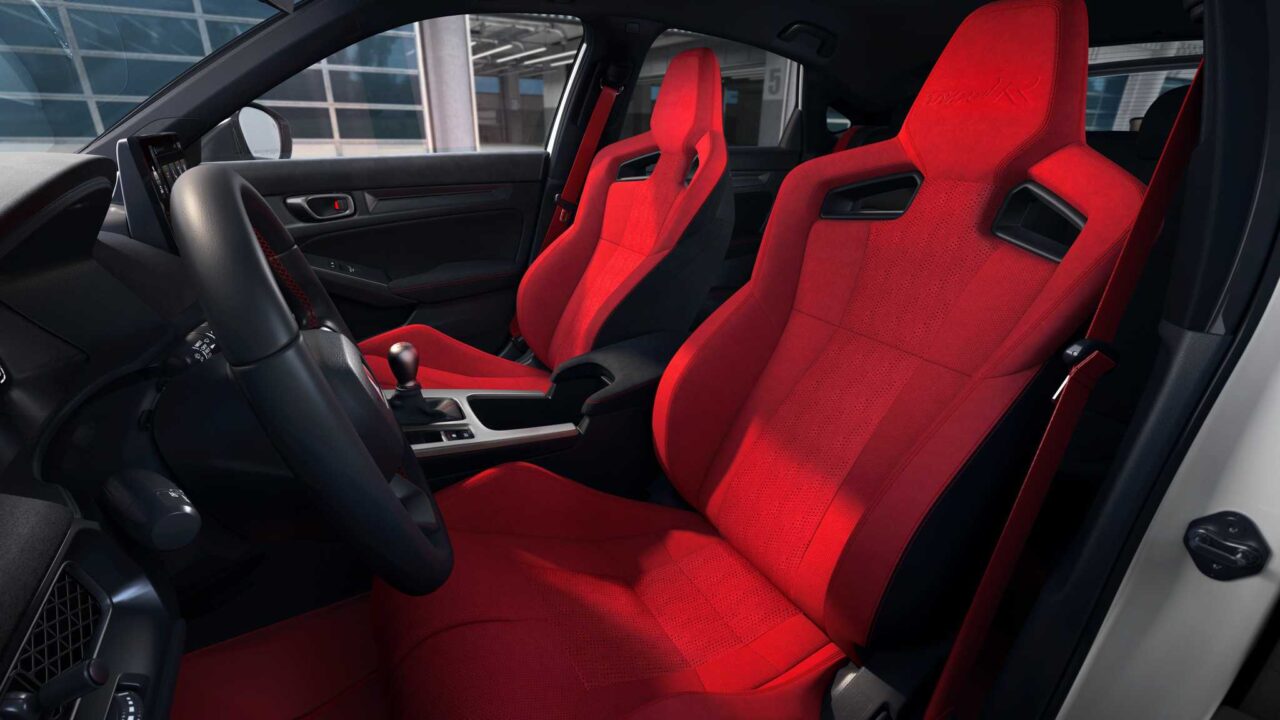 Red sports car interior with bright red bucket seats and black dashboard, gear shifter in the center console.