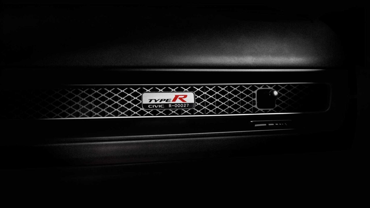 Close-up of a black car grille featuring a Type R badge reading Civic R-00027 on a mesh pattern.