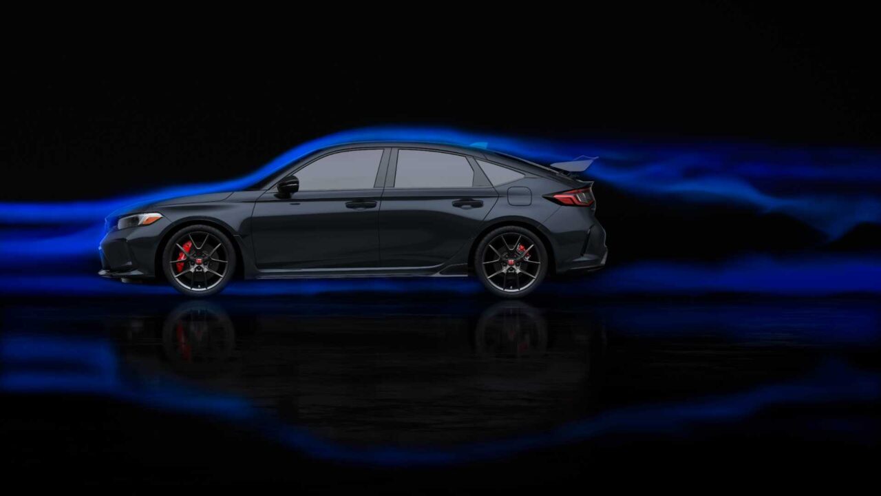 Side view of a dark gray sedan with red brake calipers, glossy finish, and blue light trails behind it against a black background, suggesting speed.
