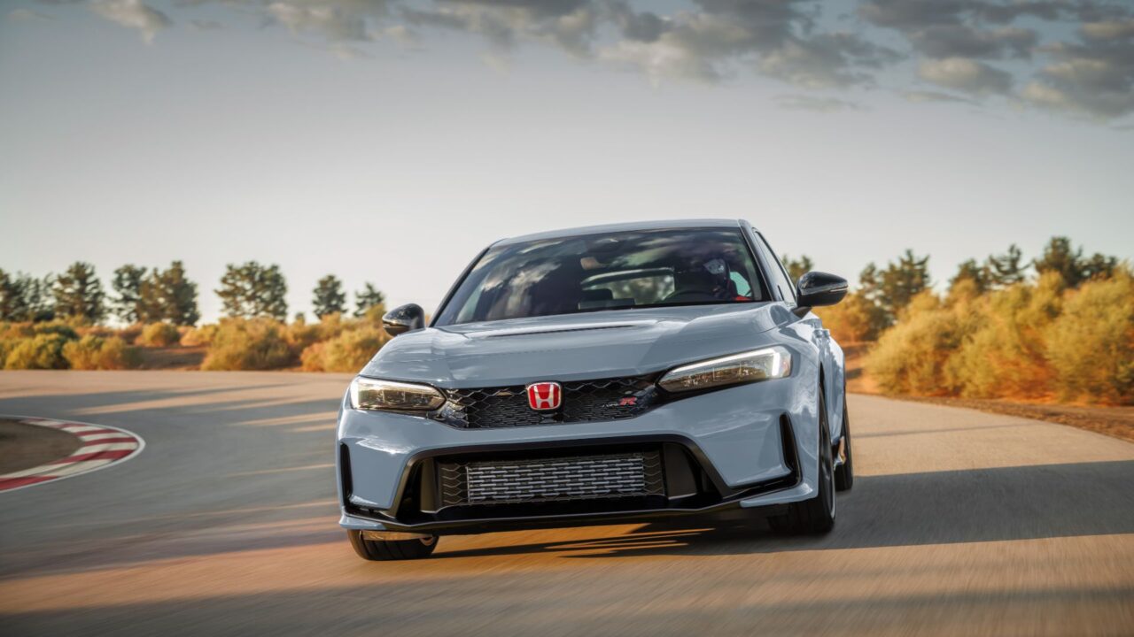 Gray Honda Civic Type R on a curving race track, captured mid-turn with autumn foliage in the background.