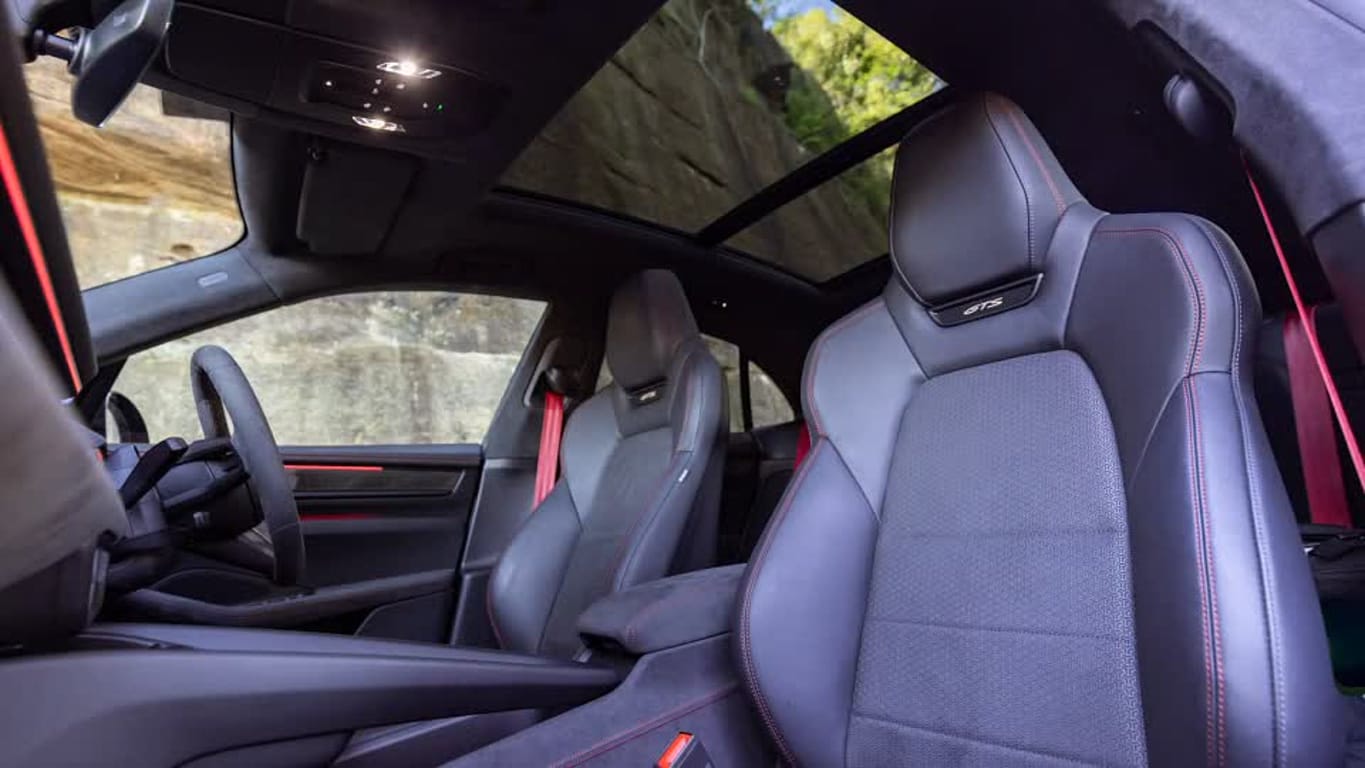 Front sport seats with red contrast stitching and a panoramic sunroof in a dark car interior (GTS branding visible).