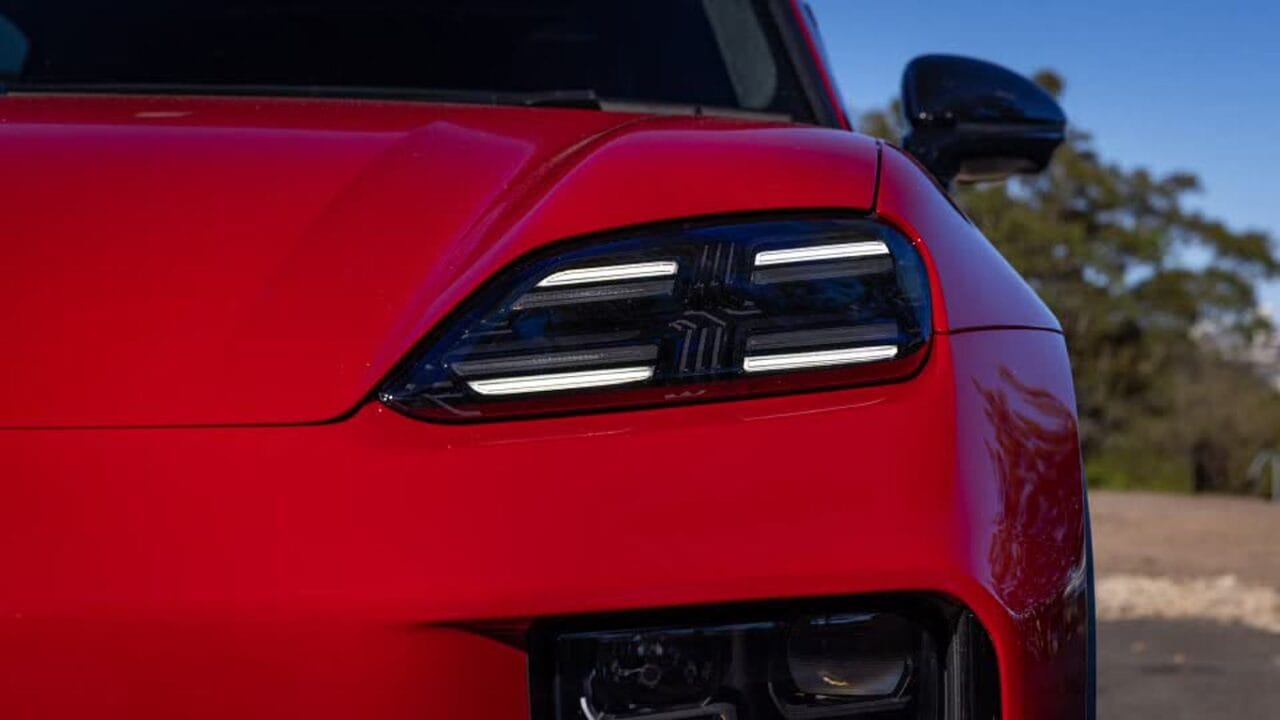 Close-up of a red sports car's angular headlight with LED daytime running lights and glossy paint