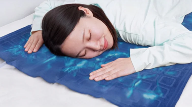 Woman lying face down with eyes closed, resting her head on a blue patterned mat on a bed