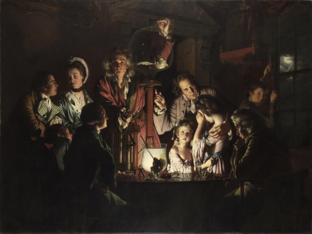 A dim, candlelit scene of people in 18th‑century clothing gathered around a table as a man in a red coat points to an oil lamp and a glass dome, with a young girl gazing upward at the lamp.