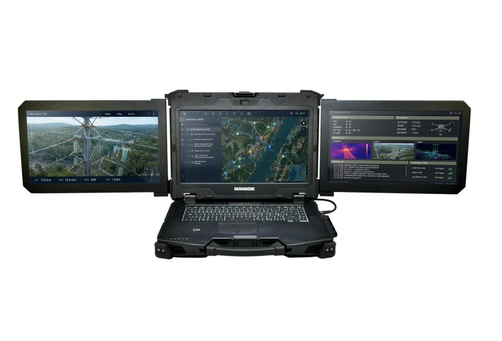 Rugged laptop with three external screens displaying a map, terrain imagery, and drone telemetry for field monitoring centralized by a tough portable computer.