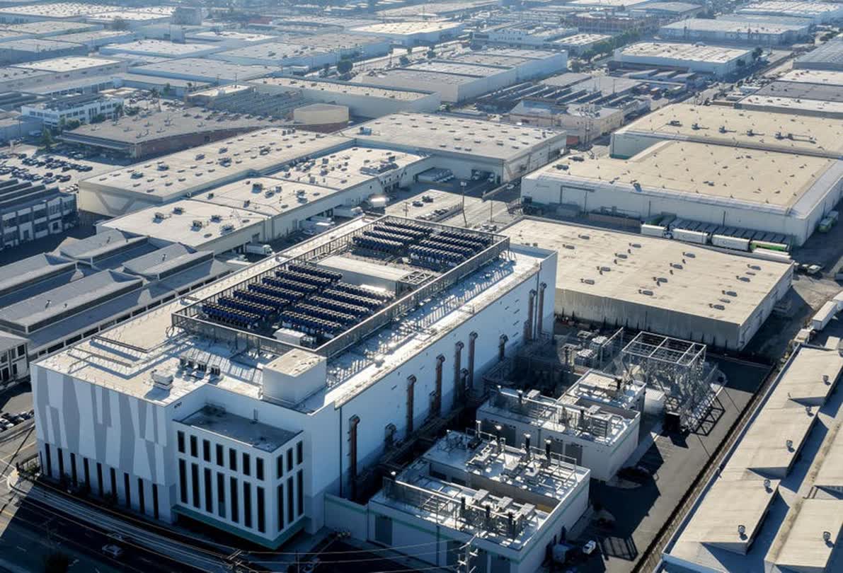 Aerial view of a large industrial campus with flat-roof buildings and solar panels on a central building.