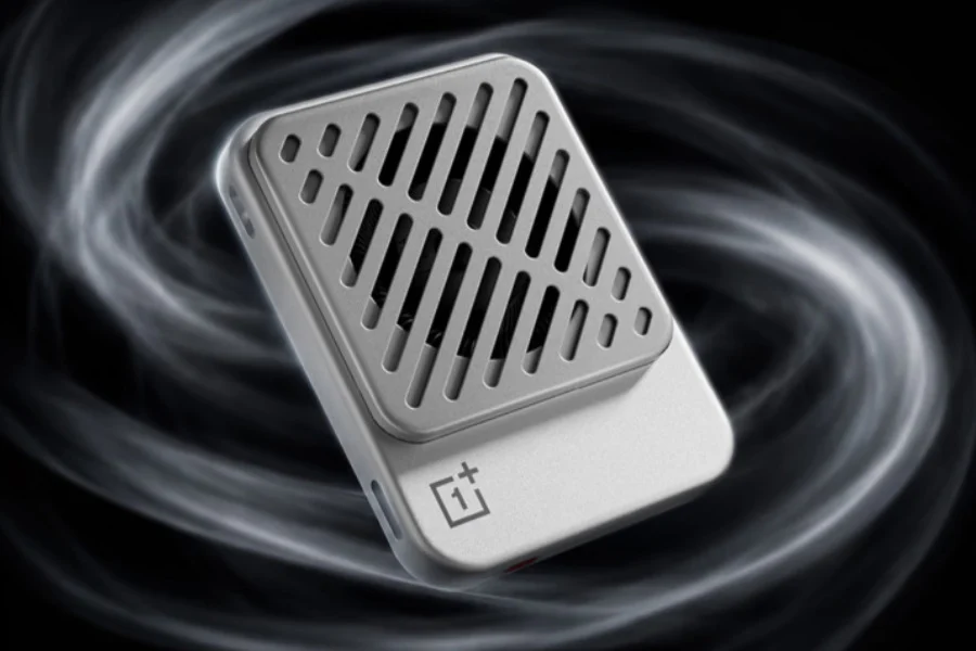 تصویر تبلیغاتی خنک‌کننده مغناطیسی OnePlus Ice Card: رندر محصولی از یک خنک‌کننده کوچک و باریک به رنگ نقره‌ای و سفید با فن داخلی و شبکه‌ای از شیارهای مورب روی بدنه و لوگوی OnePlus در پایین آن که در میان موج‌های دود مانند سیاه و سفید و روی پس‌زمینه تیره شناور است.