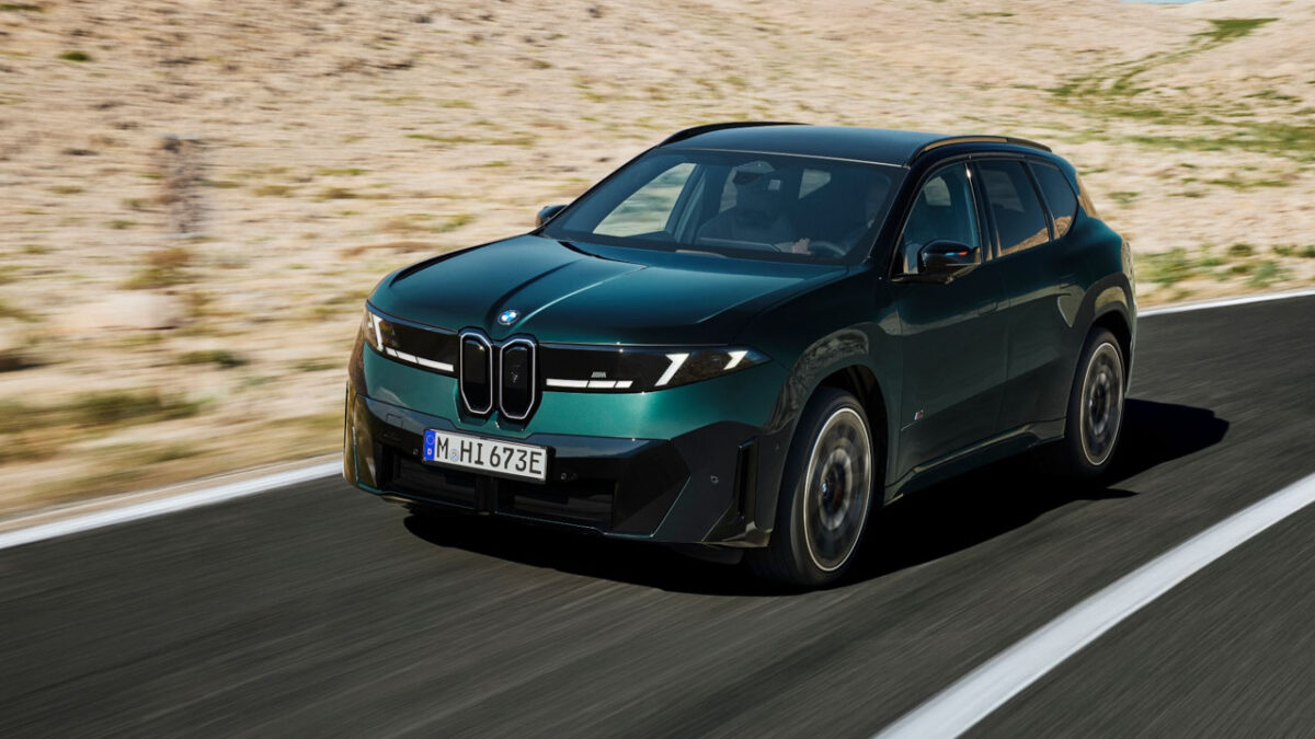نمای سه‌رخ جلوی شاسی‌بلند برقی BMW iX3 M60 xDrive با جلوپنجره کلیوی، چراغ‌های LED و بدنه سبز تیره در حال حرکت در جاده