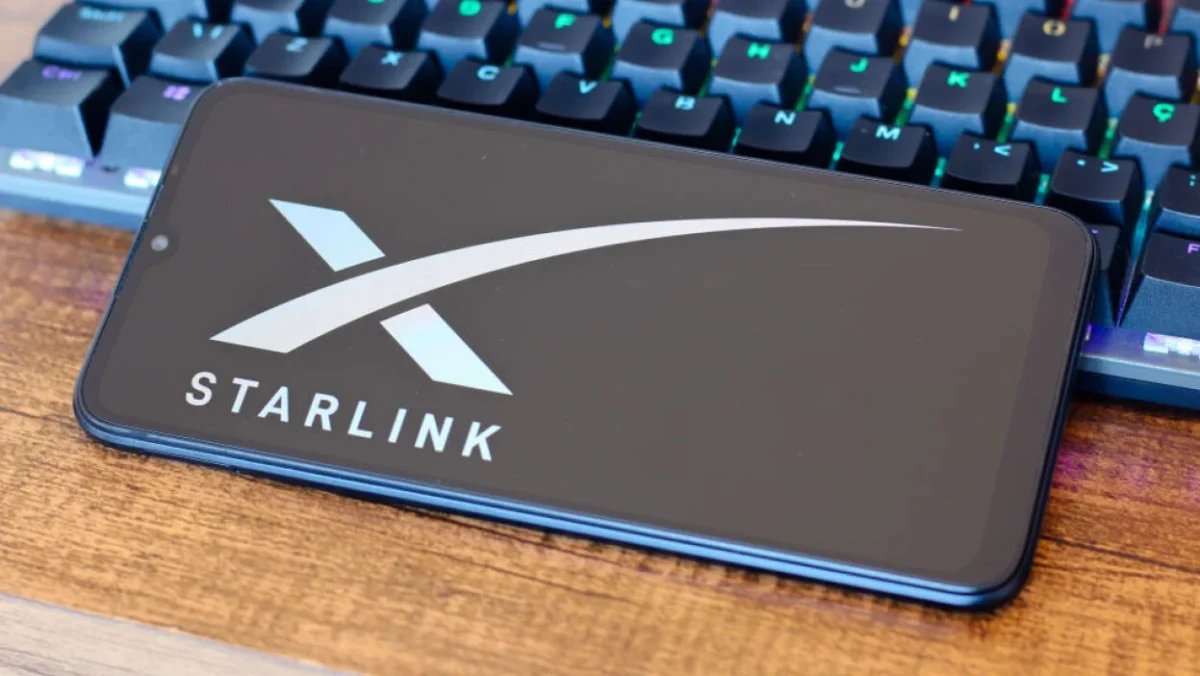 نمایش لوگوی Starlink روی صفحه گوشی هوشمند در کنار کیبورد کامپیوتر، نمادی از خدمات اینترنت ماهواره‌ای SpaceX