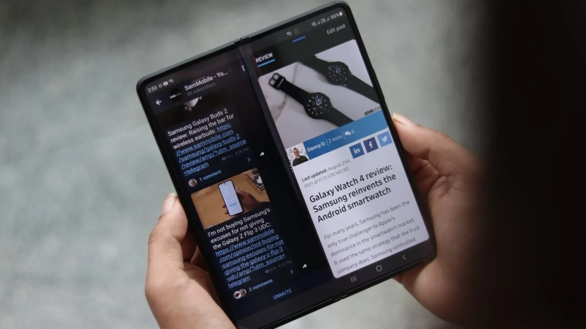 نمای نزدیک از گوشی تاشو Samsung Galaxy Z Fold 3 که در حالت باز شده و در دست گرفته شده و صفحه‌نمایش بزرگ آن دو بخش جداگانه از یک وب‌سایت خبری را به صورت Split Screen نمایش می‌دهد.