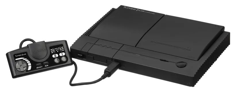 کنسول کلاسیک بازی TurboDuo به رنگ مشکی مات همراه با کنترلر سیمی اختصاصی و شیار دیسک در پس‌زمینه سفید.