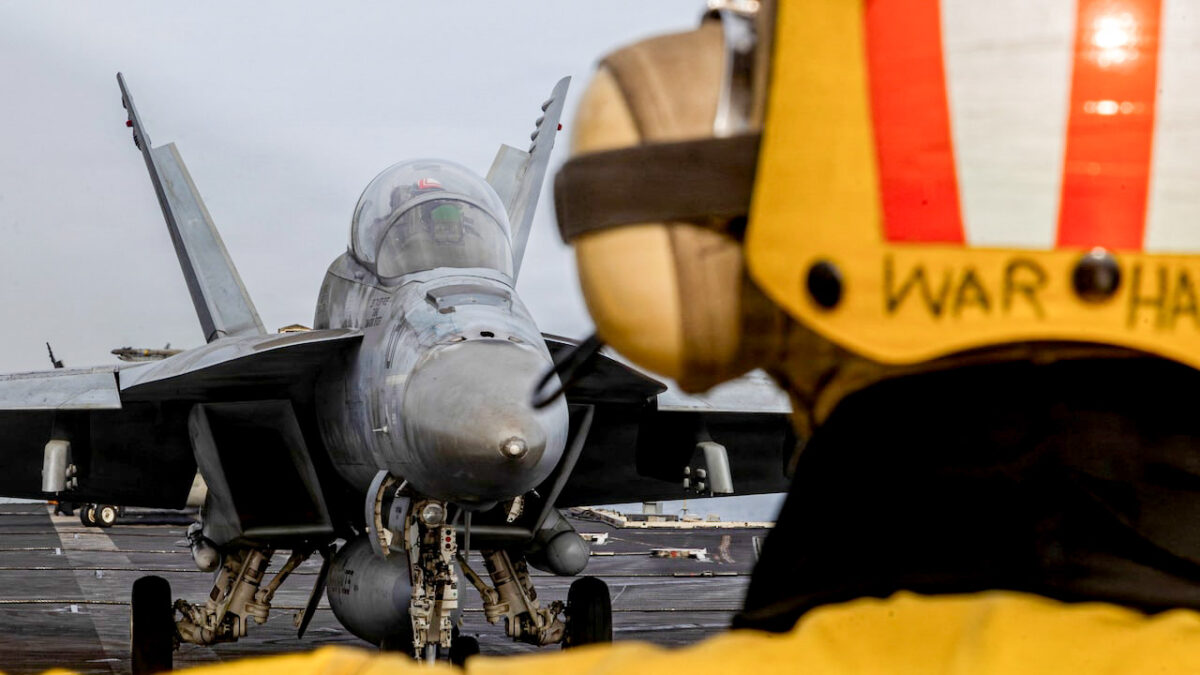 جنگنده F/A-18F سوپر هورنت روی عرشه ناو هواپیمابر نیروی دریایی آمریکا در کنار یکی از خدمه عرشه پرواز
