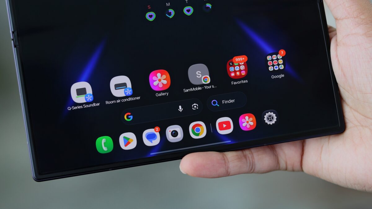 نمای نزدیک از دستی که تبلت تاشده Samsung Galaxy Z Fold 8 را باز نگرفته؛ صفحه نمایش بزرگ با ویجت‌ها و اپلیکیشن‌های خانه‌ هوشمند مانند کولر گازی و ساندبار Q-Series، در تم تیره با پیکان‌های آبی.