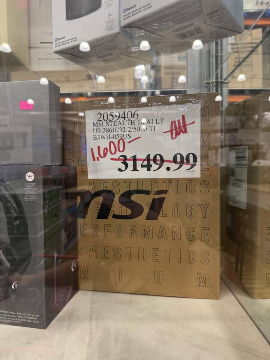 جعبه‌ی قهوه‌ای لپ‌تاپ MSI Stealth 16 AI در ویترین فروشگاه با برچسب قیمت ۱٬۶۰۰ دلار که قیمت قبلی ۳٬۱۴۹.۹۹ دلار روی آن خط خورده، کنار جعبه‌ی هدفون گیمینگ Logitech.