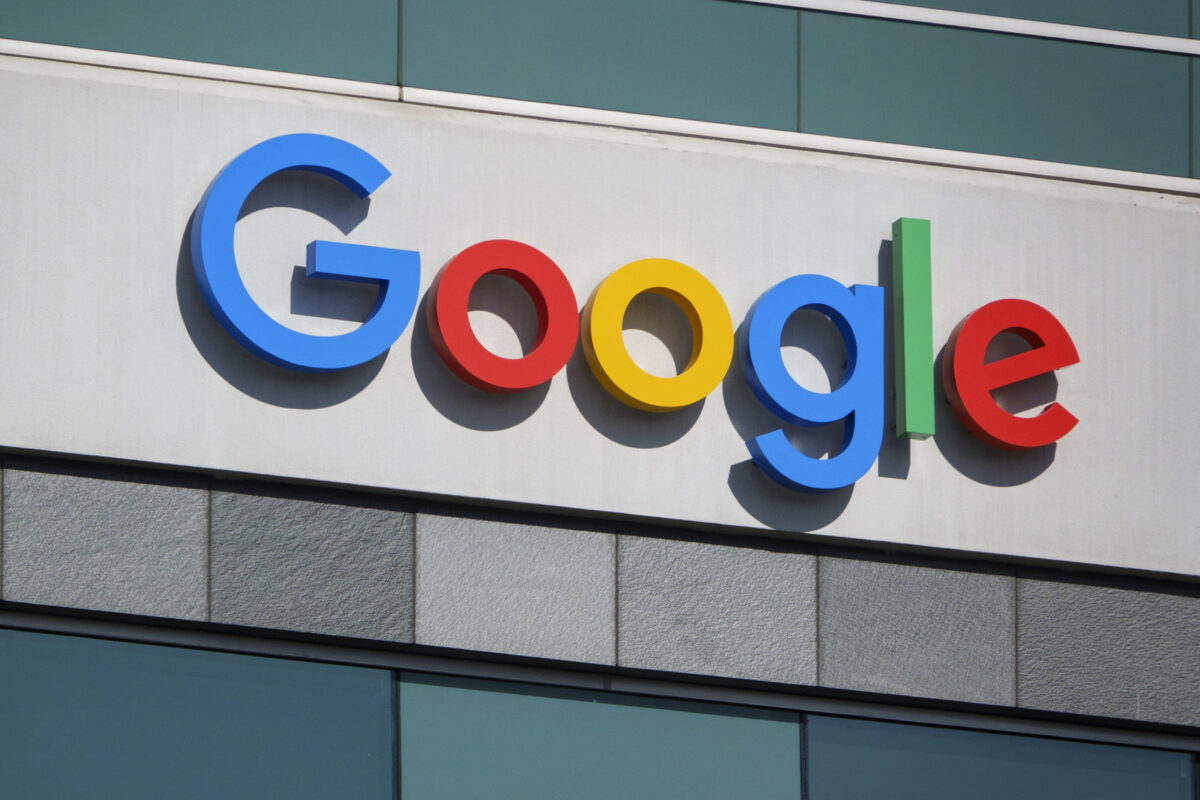 نمایی نزدیک از لوگوی برجسته و رنگارنگ Google شامل حروف آبی، قرمز، زرد و سبز که روی نمای بالای یک ساختمان مدرن نصب شده است.
