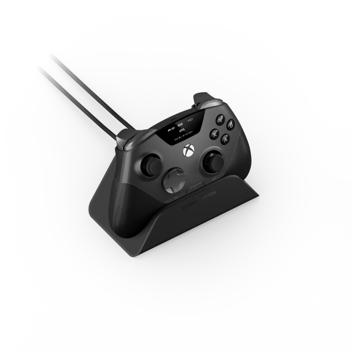 رندر استودیویی زاویه‌دار از دسته بازی مشکی SteelSeries Aeon Pro قرارگرفته روی پایه شارژ خاکستری؛ نمایشگر کوچک OLED بالای دسته با نشانگر پروفایل FPS و باتری، دو کابل بافته‌شده متصل به بخش بالایی و لوگوی SteelSeries روی استند در پس‌زمینه یکدست مشکی.