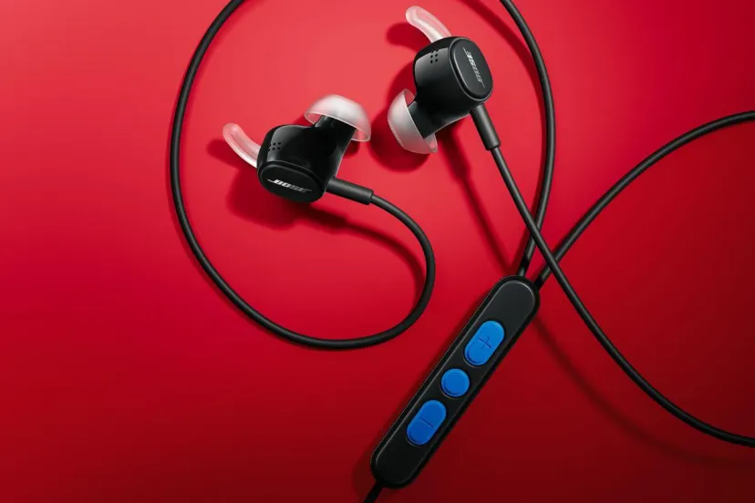 هدفون بلوتوثی ورزشی Bose با بدنه مشکی، سری‌های ژلهه‌ای شفاف داخل گوش و کنترلر دکمه‌دار آبی روی پس‌زمینه قرمز