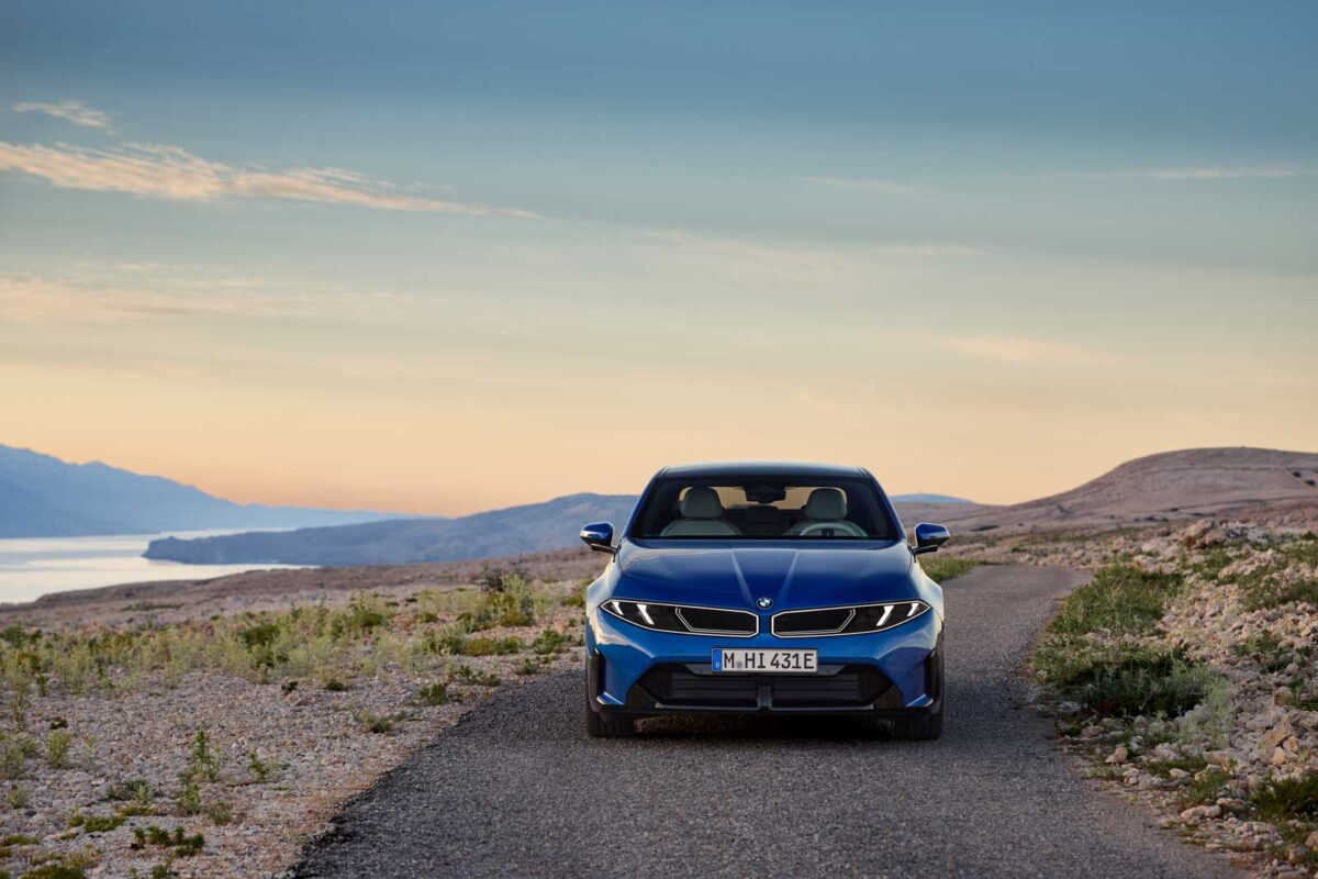 نمای روبه‌رو BMW i3 50 xDrive آبی در جاده‌ای کوهستانی