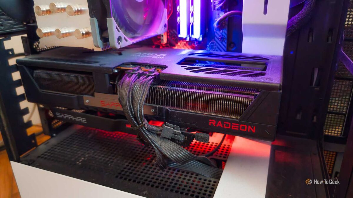 نمای داخلی کیس کامپیوتر با نورپردازی قرمز، که کارت گرافیک SAPPHIRE RADEON را با کابل‌های برق مشکی متصل به آن در مرکز تصویر نشان می‌دهد.