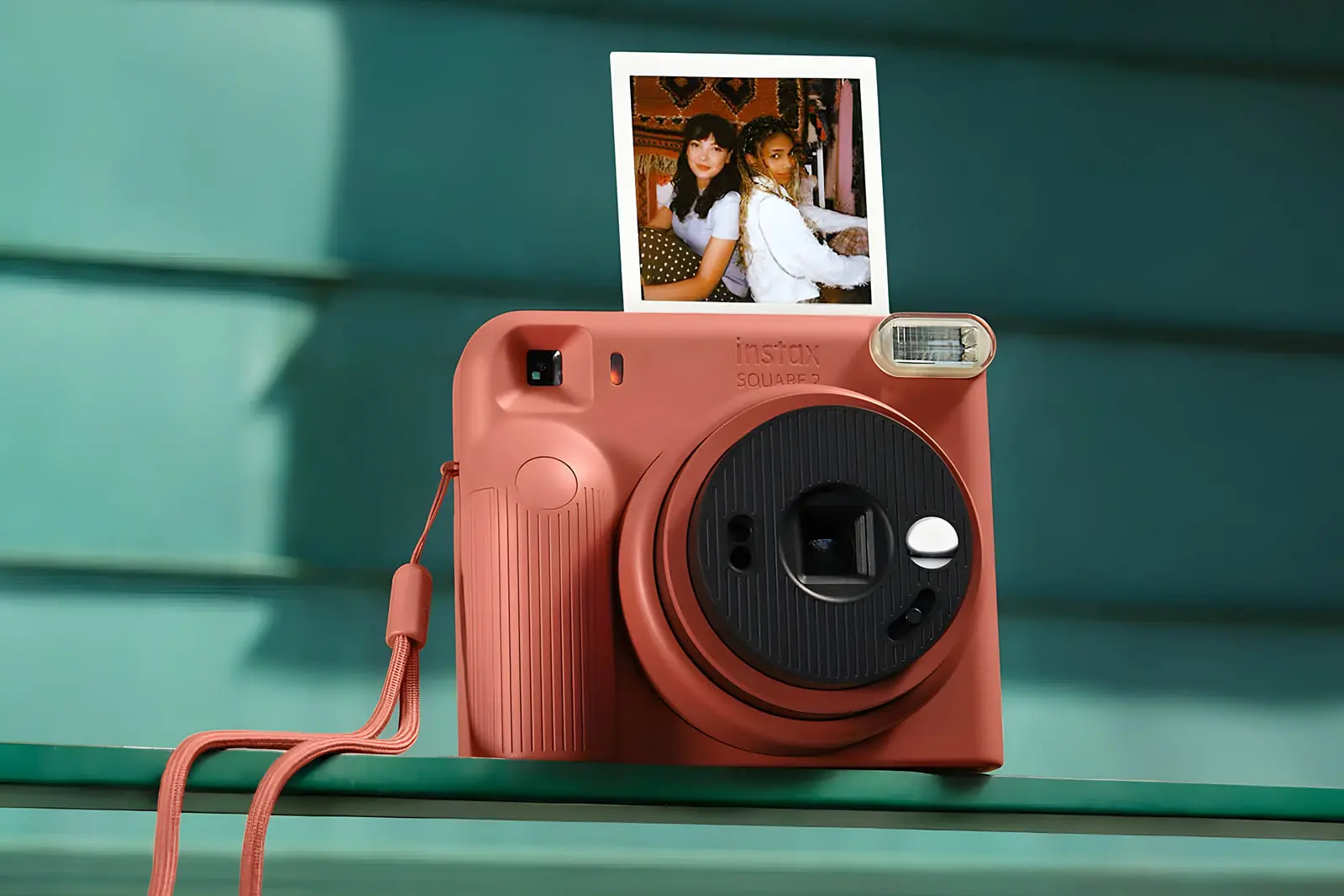 دوربین چاپ فوری اسکوئر ۲ (Instax Square 2) با رنگ تراکوتا و یک عکس چاپ شده