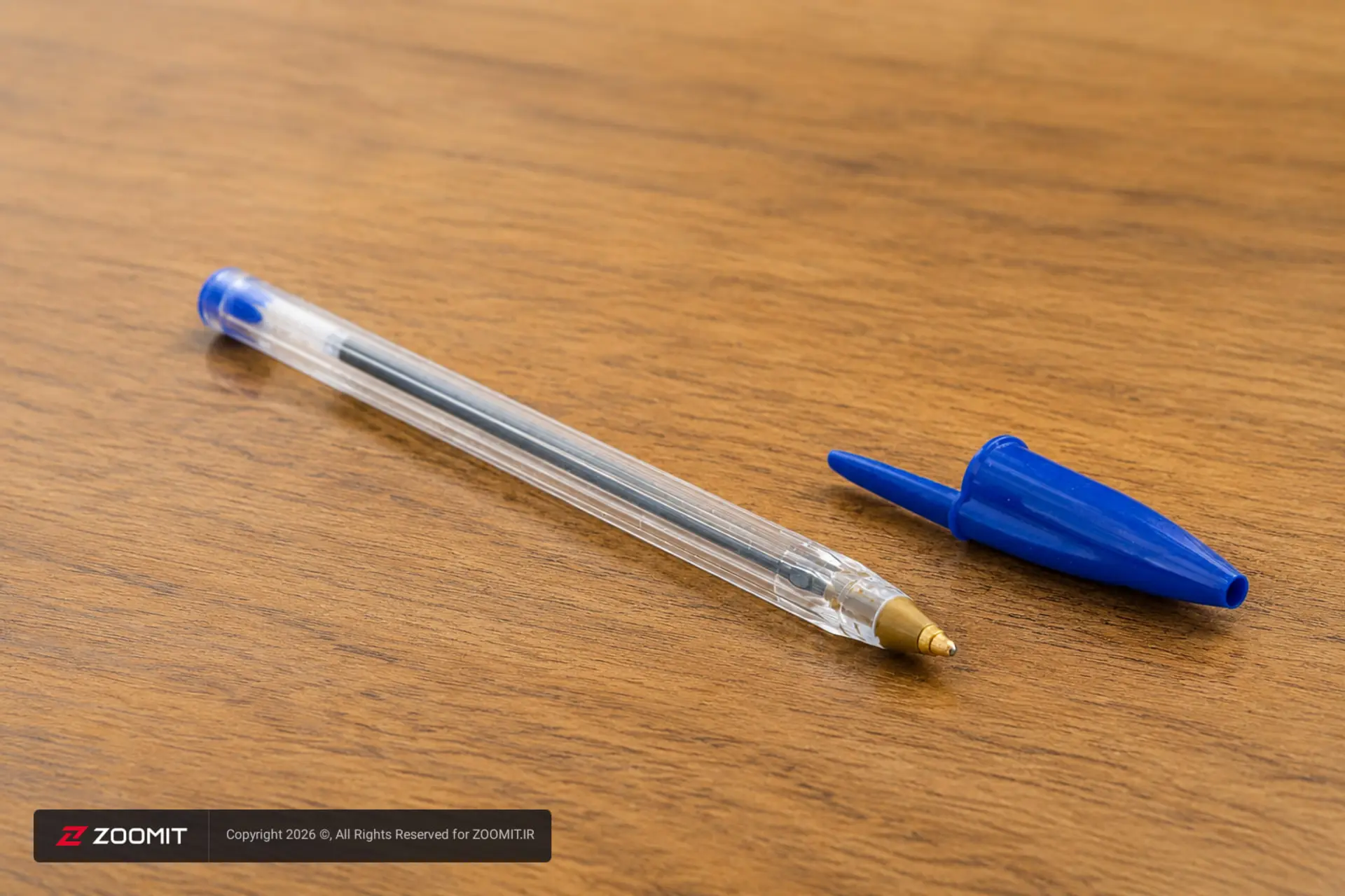 خودکار بیک کریستال (Bic Cristal) با بدنه شفاف و در آبی روی میز چوبی