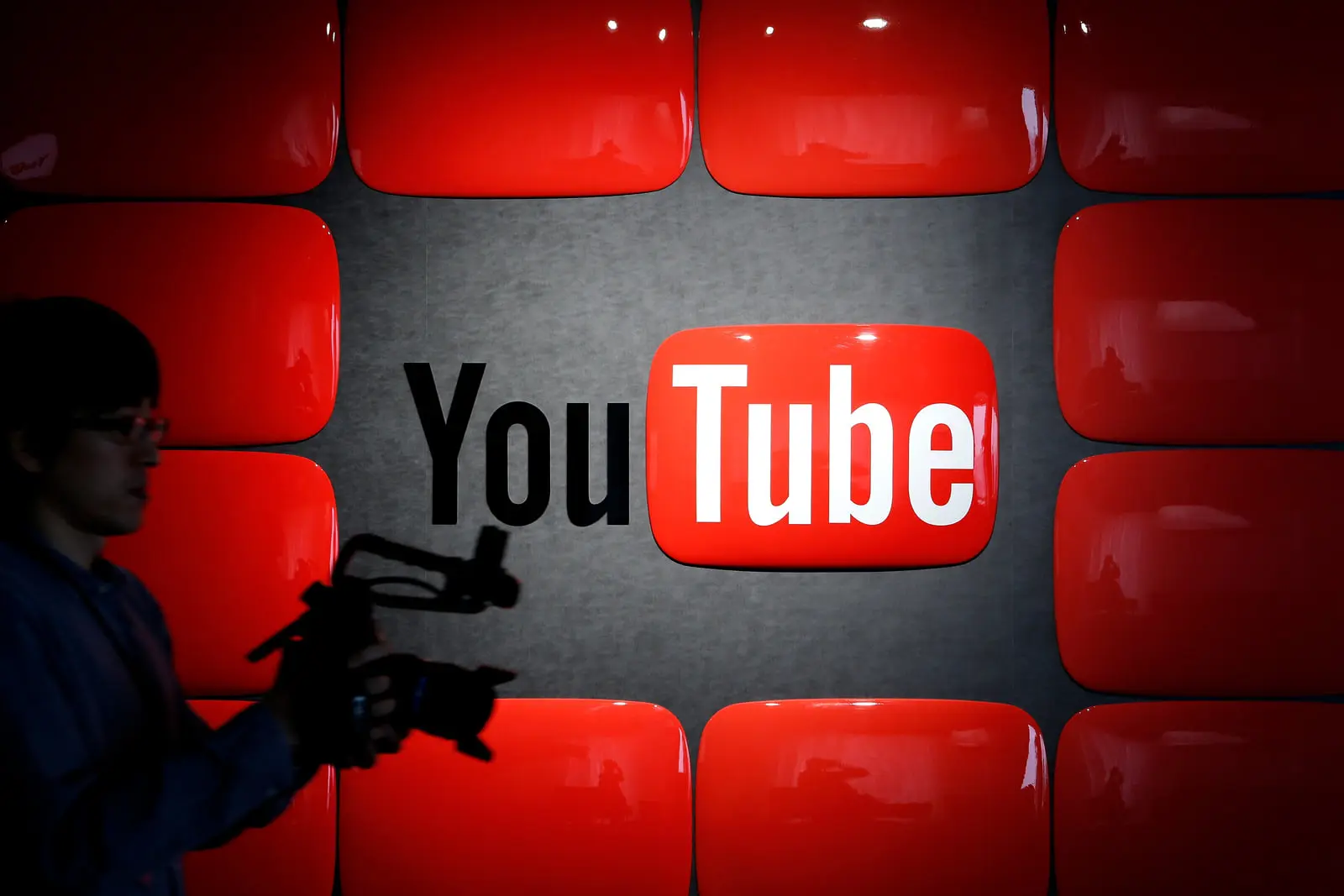 لوگوی یوتیوب (YouTube) در میان نمایشگرهای قرمز رنگ و یک فیلم‌بردار