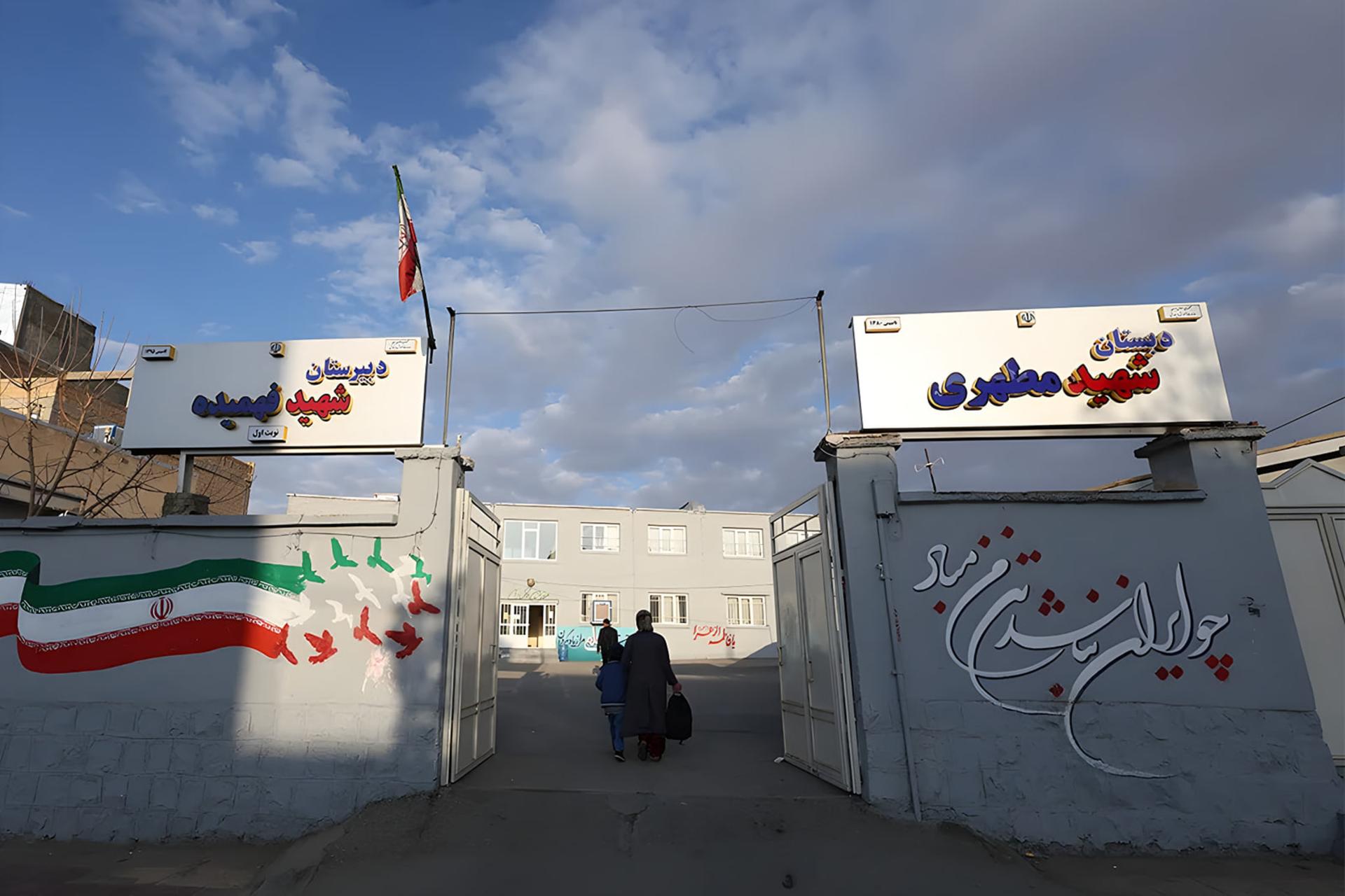 ورودی ساختمان دبستان شهید مطهری با دیوارهای نقاشی شده و پرچم ایران
