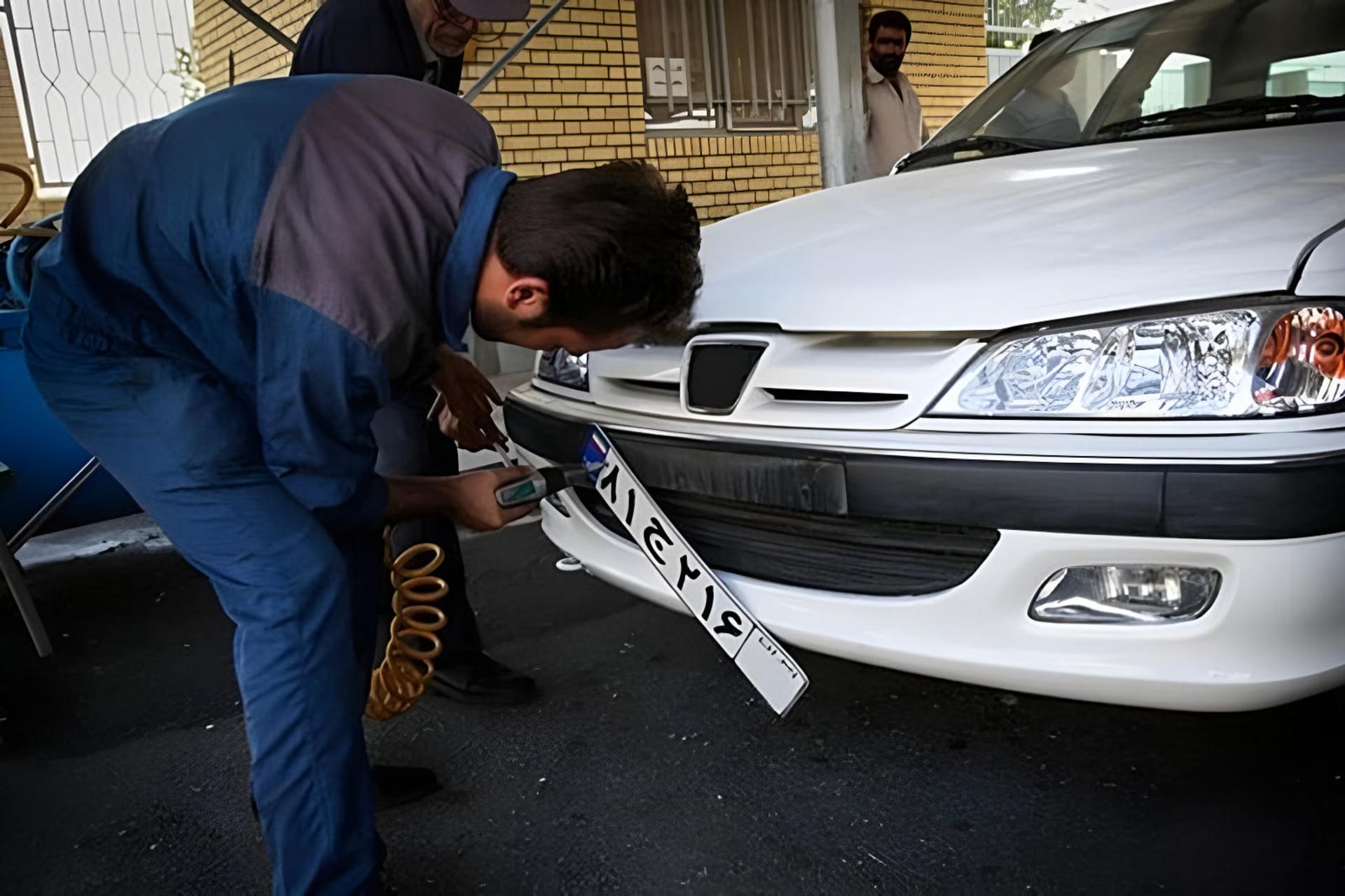 بازرسی پلاک خودروی سفید توسط کارشناس در مرکز تعویض پلاک