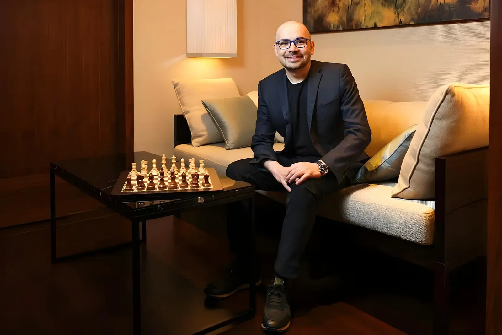 دمیس هاسابیس (Demis Hassabis) در کنار یک صفحه شطرنج چوبی